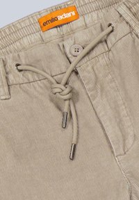 Beige Cordshorts mit einem Kordelzugbund, ausgestattet mit einem Zweiknopfverschluss und einem innen genähten Etikett. Texturierter Stoff mit vertikalen Linien.