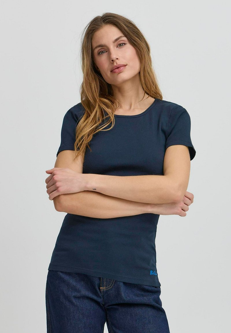 Tricou ribbed de culoare bleumarin, cu mâneci scurte și guler rotund. Are un mic logo albastru aproape de tiv. Materialul pare neted și elastic.