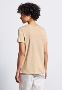 Beige tričko s krátkými rukávy a kulatým výstřihem, vyrobené z jemného materiálu, s volným střihem a přímou dolní částí. Jednoduchý design, bez vzorů.