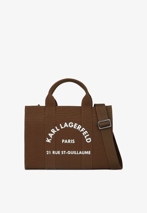 Hnědá látková taška s dvojitými uchy, nastavitelným ramenním popruhem a bílým potištěným textem. Obdélníkový tvar s texturovaným povrchem.