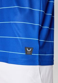 Polo shirt da uomo blu con righe azzurre, tessuto strutturato e un'etichetta nera con un logo ad ali e il testo "PRODOTTO AUTENTICO CASTORE".