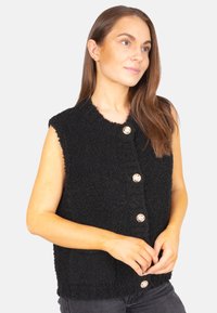 Schwarze ärmellose Weste aus strukturiertem Material, mit fünf runden, metallischen Knöpfen auf der Vorderseite und einem runden Ausschnitt.