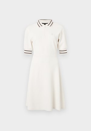 Poloshirtjurk in crème met korte, opgeblazen mouwen en bruine gestreepte accenten op de kraag en mouwen. Heeft een halve rits aan de voorkant.