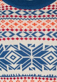 Stickad tröja med en blå krage, geometriska mönster i blått, röd, rosa och orange på en krämfärgad bakgrund med varierande texturer.