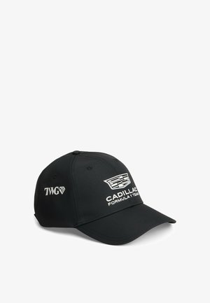 Sort baseballkasket med hvid Cadillac Formula 1 Team-logo foran og TWG-logo på siden, vinklet mod højre på en hvid baggrund.