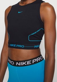 Zwarte Nike Pro sport crop top met turquoise accenten, voorzien van een ronde hals en een aansluitende pasvorm, aangevuld met een elastische band met merknaam.