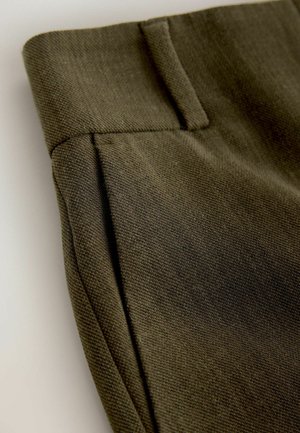 Olive green trousers featuring a textured fabric, tapered shape, and side pockets with a clean waistband and tailored seams.