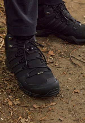 Botas de senderismo negras con parte superior sintética, paneles texturizados, puntera reforzada, suela acolchada y marca GORE-TEX en el lateral.