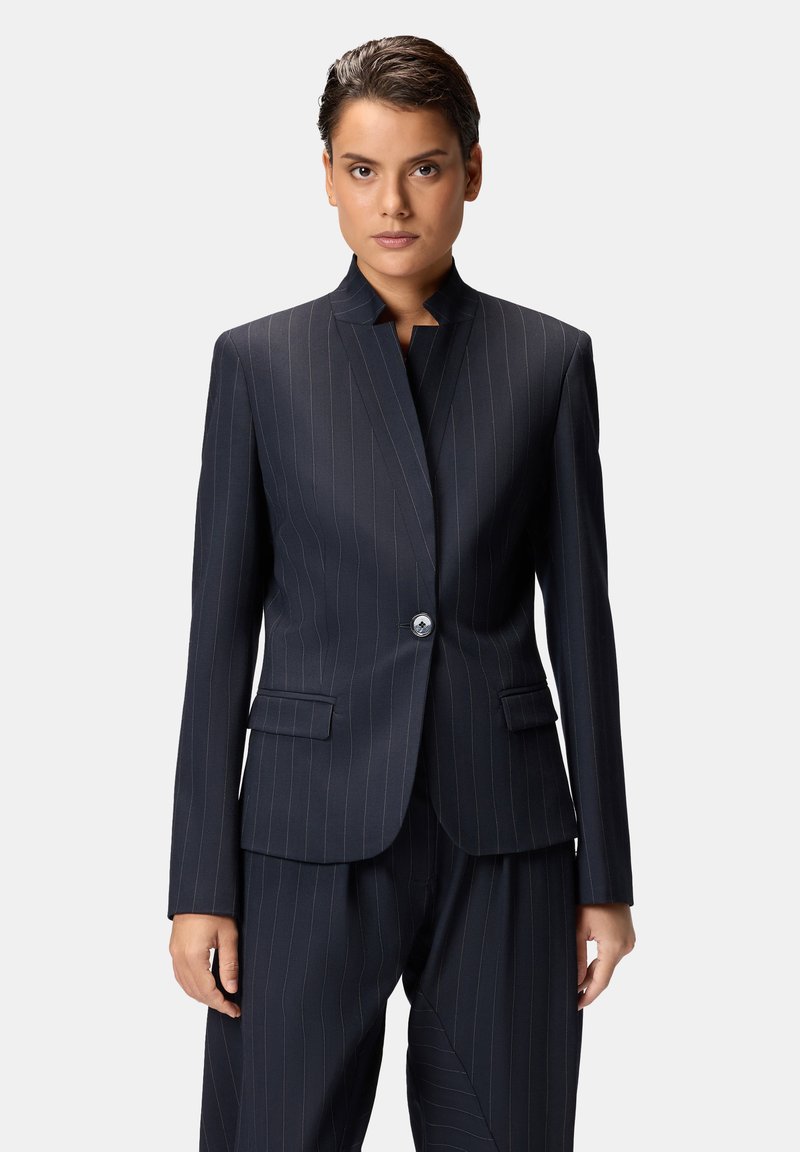 Blazer a righe sottili navy con colletto alto, chiusura con un solo bottone e tasche con pattina, realizzato in un tessuto liscio e leggero.