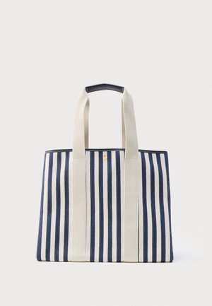 Marineblå og hvide vertikale stribede shoppertaske med brede cremefarvede håndtag og en lille gulddetalje i form af en knap øverst i midten.
