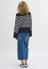 Navy and white striped cropped sweater paired with a long blue denim skirt and black-and-white sneakers; soft textures, casual fit.