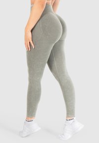 Leggings a vita alta, verdi oliva, con tessuto testurizzato e dettagli a costine, caratterizzati da un design seamless e una silhouette aderente.