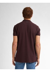 Burgundowa koszulka polo z miękkim materiałem bawełnianym i klasycznym kołnierzykiem. Krótkie rękawy i subtelny detal z logo na tylnej części dekoltu.