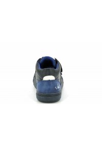 Zapatilla negra y azul con parte superior de ante y cuero texturizados, tiras de Velcro, cuello acolchado y suela de caucho. Acento blanco cerca del talón.