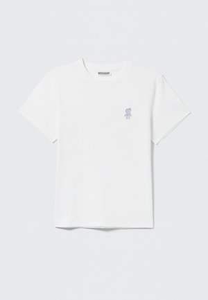T-shirt en coton blanc à manches courtes, avec une petite broderie d'un ours violet sur le côté gauche de la poitrine. Design à col rond.