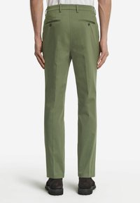 Gröna bomullsbukser med rak passform, som har två bakfickor med knappar och en pressveck framtill. Bärs med mörka skor.