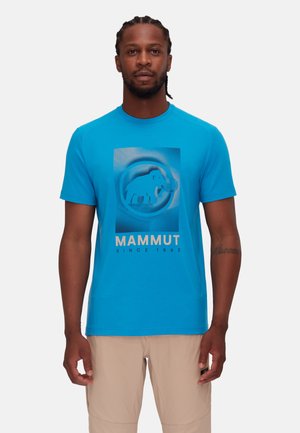 Niebieska bawełniana koszulka z centralnym motywem słonia w okrągłym obramowaniu, z napisem "MAMMUT SINCE 1862" poniżej w wyraźnej czcionce.
