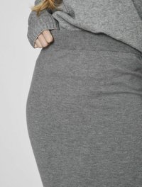 Pull en maille gris avec des bords-côtes aux poignets et à la taille, présentant une texture lisse et une silhouette ajustée, montrant un gros plan sur le tissu.