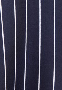 Tissu bleu foncé avec des fines rayures blanches verticales régulièrement espacées sur toute la surface.