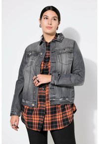 Harmaa farkkutakki, jossa on napit, kaksi rintataskua ja rento istuvuus, kerroksittain oranssin ja mustan ruudullisen paidan päällä.