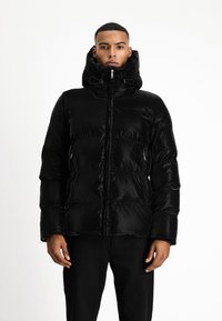 Chaqueta de plumas negra con un cuello alto, cierre delantero con cremallera y bolsillos laterales. Tiene una textura brillante y un patrón acolchado en toda su superficie.