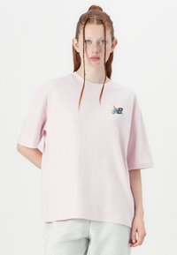 Light pink oversized t-shirt in soft cotton, with short sleeves and a round neckline. Features a multicolored logo on the left chest.