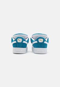 Baskets en daim bleu sarcelle avec accents blancs. Dotées d'un col rembourré, d'un logo doré au talon et d'une semelle en caoutchouc blanche texturée. Design classique.