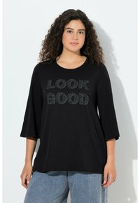 Zwart, loszittend shirt met 3/4 klokmouwen, met de tekst "LOOK GOOD" in een patroonontwerp. Zacht materiaal, casual pasvorm.