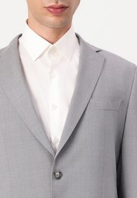 Light gray suit jacket made of textured fabric, featuring a notched collar, single button closure, and a chest pocket. White shirt underneath.
