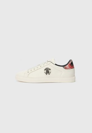 White low-top sneaker with laces, black emblem on the side, and red and black patterned heel tab with dragon design.