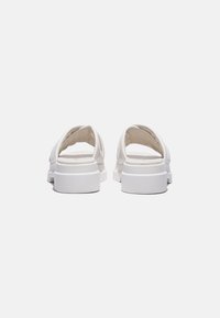 Witte open sandalen met een soepel materiaal, platte zool en een minimalistisch ontwerp, met subtiele stiksels en een ronde vorm.