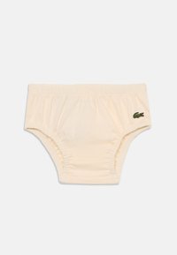 Sous-vêtements briefs de couleur crème avec une taille élastique, ornés d'un petit logo de crocodile vert sur le côté droit.