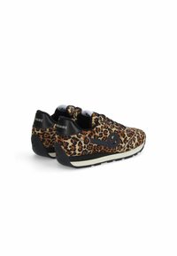 Schoenen met luipaardprint, voorzien van een textielen bovenwerk, zwarte accenten en een laag profiel. Beschikt over een witte tussenzool en een zwarte buitenzool.