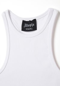 Weißes, geripptes Tanktop mit rundem Ausschnitt, ausgestattet mit einem schwarzen Etikett, auf dem "Utopia XS" steht. Der Stoff ist glatt und eng anliegend.