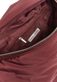 Bordeaux színű táska belseje sima textúrájú, zipzáras zsebbel és "InWear" márkainformációt tartalmazó címkével rendelkezik. Ezüst színű zipzár felszerelés.