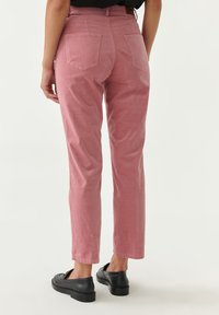 Roze corduroy broek met een slim fit, voorzien van achterzakken en een middelhoge taille. Gemaakt met zwarte instap schoenen. Soepele textuur.