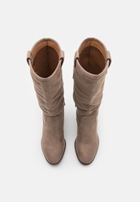 Bottes en daim couleur marron clair, montantes jusqu'aux genoux, avec un design froncé, des bouts ronds et une doublure intérieure douce. Comprend des anses de tirage sur les côtés.