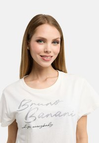 Weißes Baumwoll-T-Shirt mit metallischem Schriftzug "Bruno Banani" und "nicht für jedermann" auf der Vorderseite, Rundhalsausschnitt und kurzen Ärmeln.