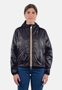 Giacca leggera nera con cappuccio, dotata di una zip frontale con un accento giallo, polsini elasticizzati e una texture liscia e sinuosa.