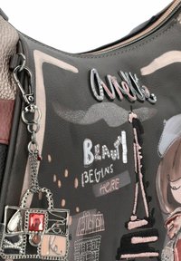 Graue Lederhandtasche mit bunten gestickten Motiven, einem metallischen Charm und dekorativen Textelementen, einschließlich "Schönheit beginnt hier."