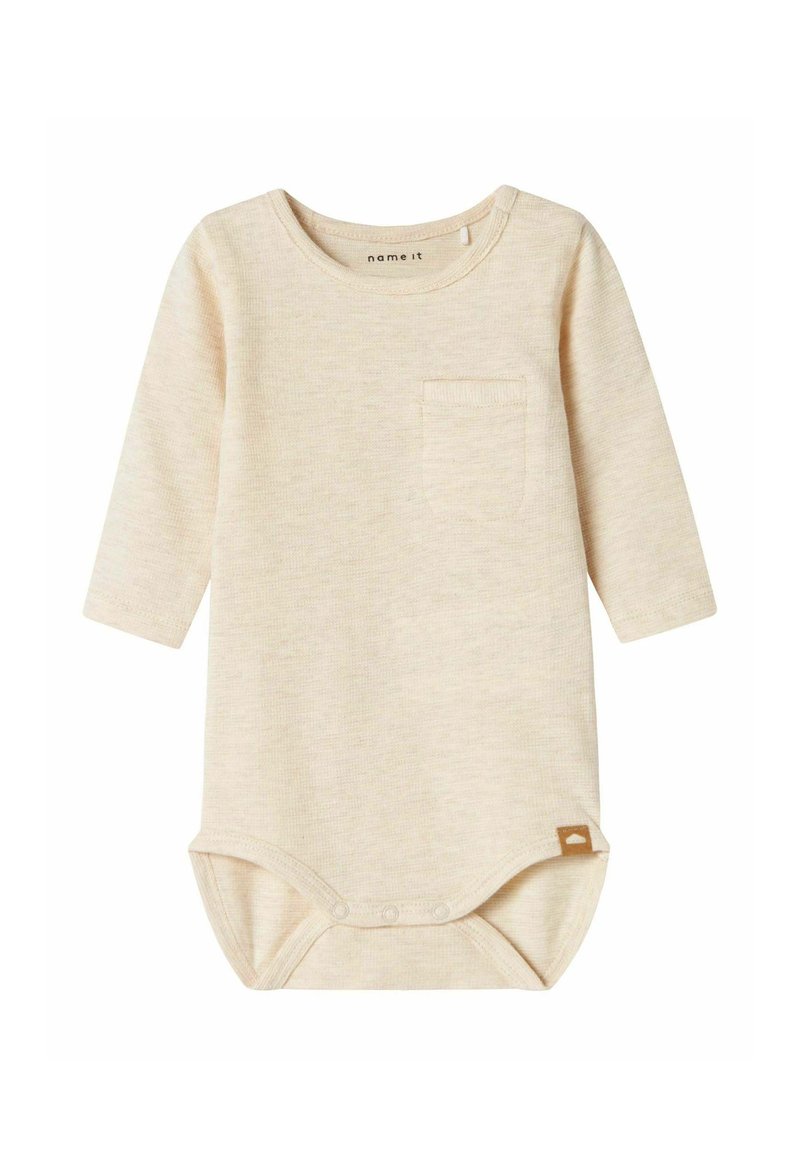 Body pour bébé à manches longues en beige clair, texture côtelée, avec une poche poitrine et des boutons-pression au bas. Accents en étiquette marron.