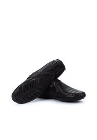 Schwarze Slipper aus perforiertem Obermaterial, mit gummierter, strukturiertem Sohle und flexibel gestaltet. Verfügt über minimalistische Akzente in Rot an den Seiten.