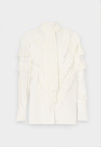 Blusa blanca con volantes en capas en el frente, mangas largas y una corbata de cuello plisada. Textura suave con una silueta estructurada.