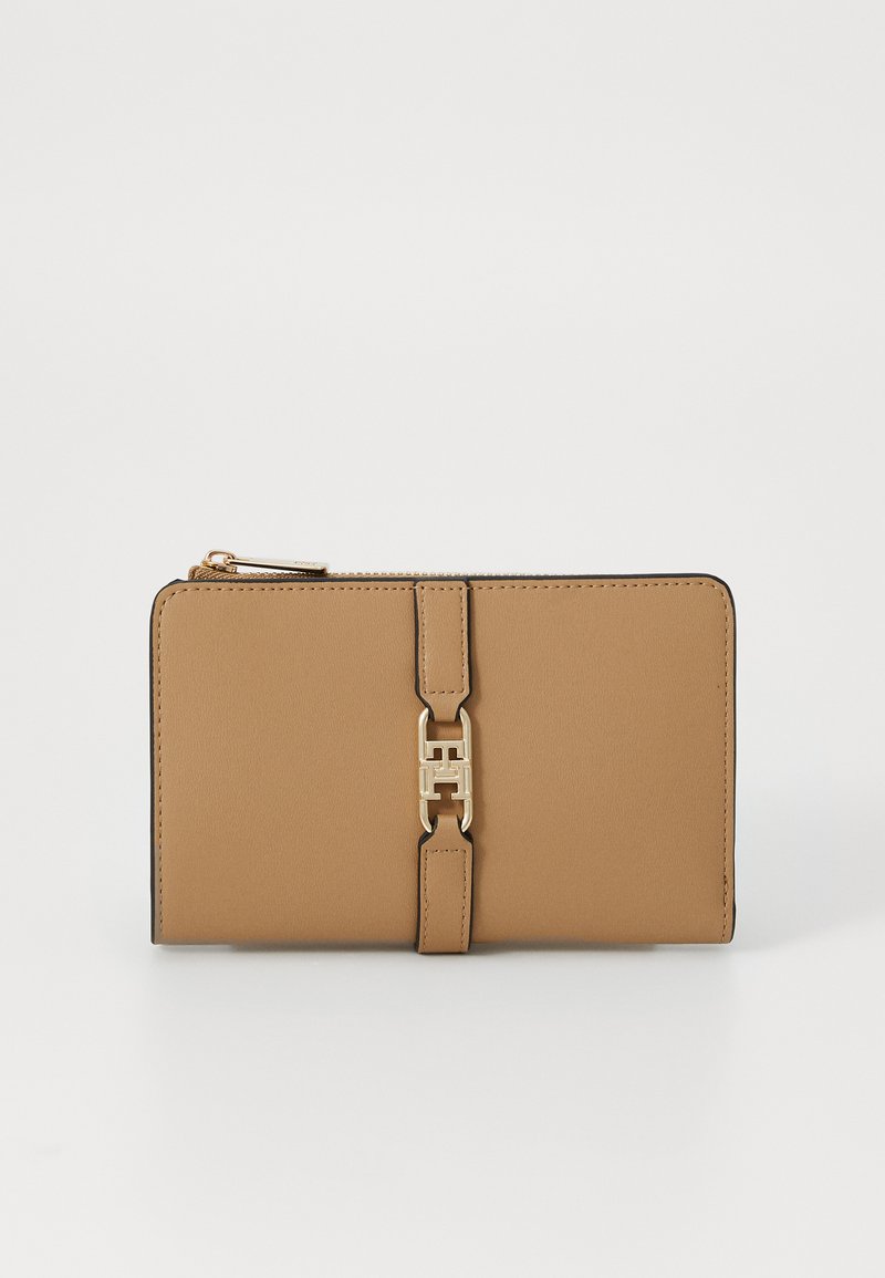 Tan leren portemonnee met een gladde textuur, gouden hardware-accent in het midden en een ritsafsluiting langs de bovenrand.