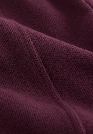 Strickstoff in einem tiefen Burgunderrot, mit einer strukturierten, gerippten Musterung und weichen, flauschigen Oberflächendetails.
