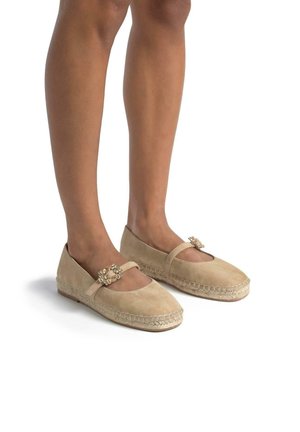 Scarpe flat in suede beige con punta rotonda, cinturino alla caviglia e fibbia decorativa. Presentano dettagli intrecciati lungo il bordo.