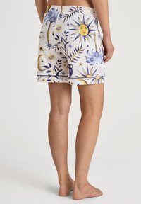 Shorts i vitt tyg med ett gult och blått himmelskt tryck, inklusive sol-, mån- och blomstermönster. Resårmidja och avslappnad passform.