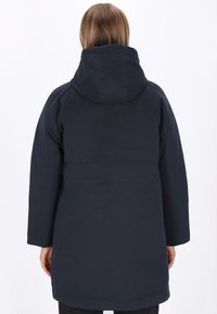 Marineblauwe parka met capuchon, voorzien van een eenvoudig ontwerp, raglanmouwen en een rechte snit aan de zoom, gemaakt van lichte stof.