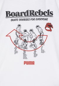 Hvit t-skjorte med svarte og røde grafikker. Teksten sier "BoardRebels" og "SKATE COURSES FOR EVERYONE." Illustrasjonene viser skatingteknikker.