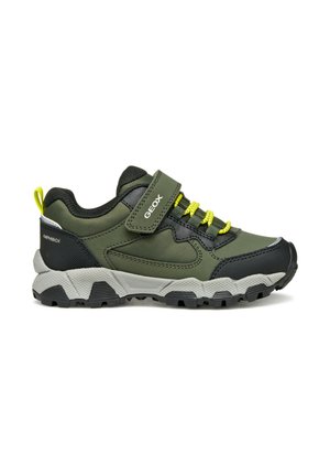 Chaussure de sport verte et noire avec un extérieur texturé, des lacets élastiques, une sangle Velcro et une semelle gris robuste avec un motif de traction noir.